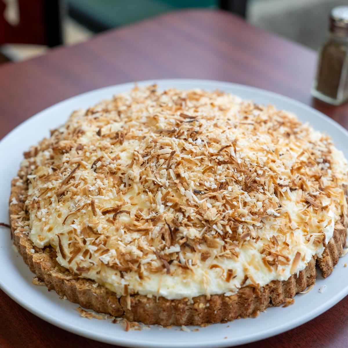 A whole homemade toasted coconut cream pie in a graham cracker crust.
